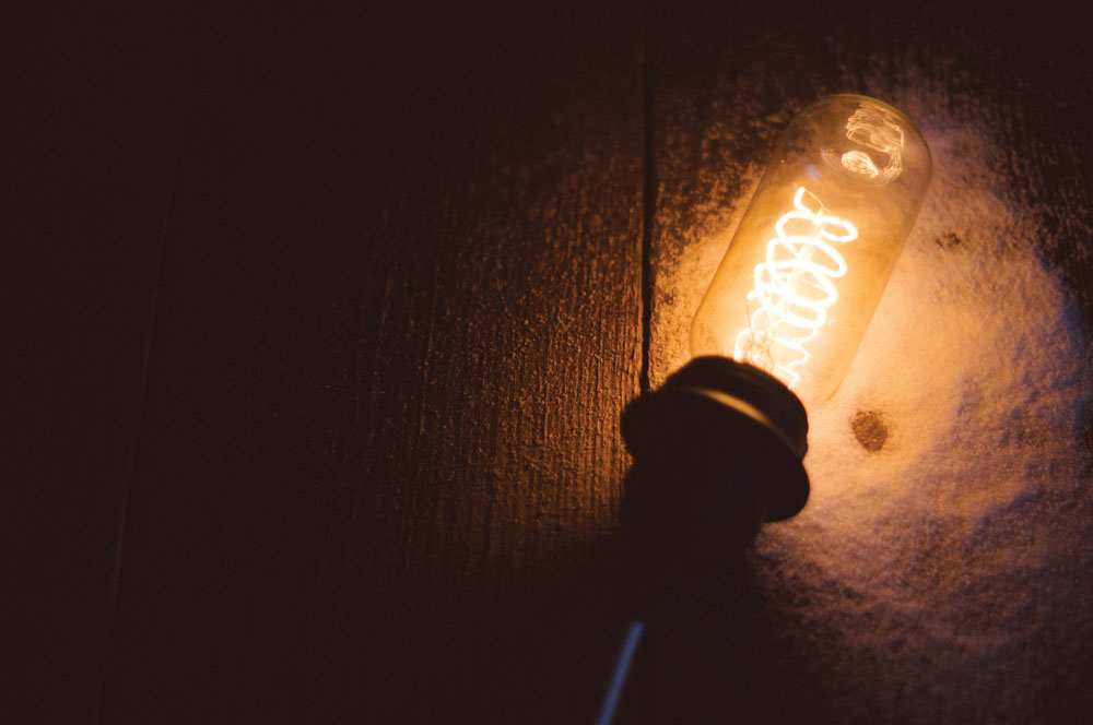 light bulb (on) against a dark wood floor