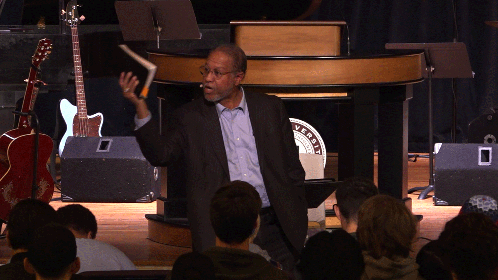 Dr. Tony Hurst standing on the floor of the chapel with a Bible in hand